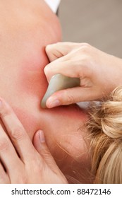 Female Receiving Gua Sha Treatment To Neck And Shoulders