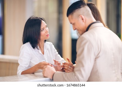 female receptionist at counter in hotel with Young couple receiving tourist information - Shutterstock ID 1674865144