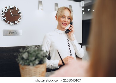 Female Receptionist In Hotel Talking On The Phone At Work