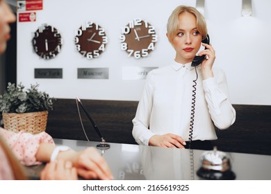 Female Receptionist In Hotel Talking On The Phone At Work