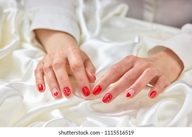 Female red manicure and white silk. Young woman hands with red heart pattern nails on white silk fabric. Concept of woomanhood and delicacy. - Shutterstock ID 1115516519