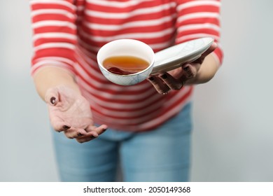 A female in red and white stripy shirt dropping teacup with tea, selective focus - Shutterstock ID 2050149368