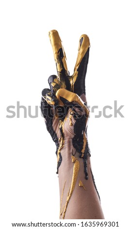 Female refined hand smeared with black and gold acrylic paint on a white background