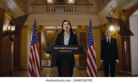 Female republican politician or minister gives political speech in the White House. US government representative speaks at press conference for media and television. American flags in the background. - Powered by Shutterstock