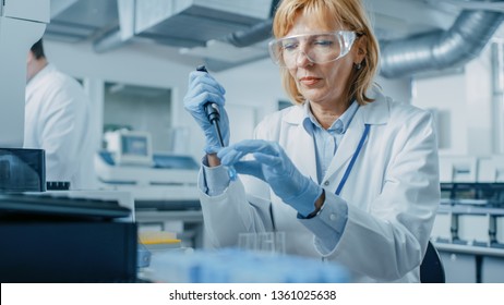 Female Research Scientist Uses Micro Pipette while Working with Test Tubes. People in Innovative Pharmaceutical Laboratory with Modern Medical Equipment for Genetics Research.