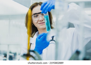 female researcher, medical scientist or doctor with test tube of clear liquid in laboratory, chemist developing concept