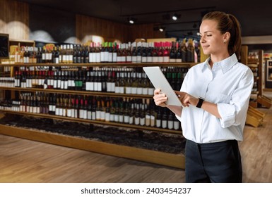 Female retail manager working in liquor store, using digital tablet in front of blurred shelves with wine bottles. - Powered by Shutterstock