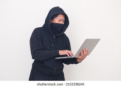 Female Robber Wearing Black Balaclava And Hoodie For Disguise, Working On Her Computer To Hack Bank Security System