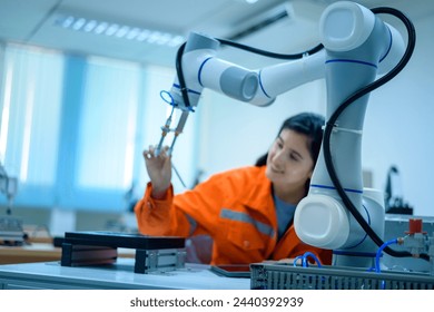 Female Robotics engineer working with Programming and Manipulating Robot Hand, Industrial Robotics Design, High Tech Facility, Modern Machine Learning. Mass Production Automatics.