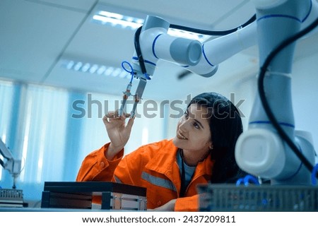 Female Robotics engineer working with Programming and Manipulating Robot Hand, Industrial Robotics Design, High Tech Facility, Modern Machine Learning. Mass Production Automatics.