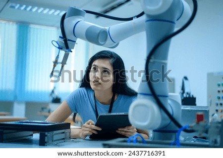 Female Robotics engineer working with Programming and Manipulating Robot Hand, Industrial Robotics Design, High Tech Facility, Modern Machine Learning. Mass Production Automatics.