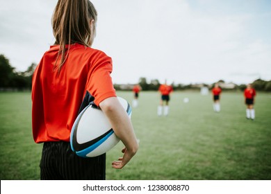 Female rugby player holding the ball in her arms - Powered by Shutterstock