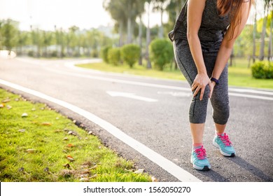 Female runner athlete knee injury and pain. Woman suffering from painful knee while running in the park.