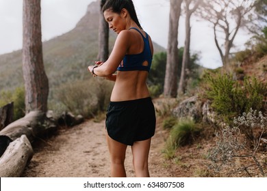 Female Runner Checking Fitness Progress On Her Smart Watch. Asian Woman Using Fitness App To Monitor Workout Performance, While Walking Through Mountain Trail.