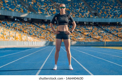 Female Runner Getting Ready To Warm Up And Workout Before Running. Female Athlete Standing Inside A Track And Field Stadium Ready.