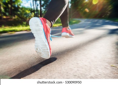 Female runner jogging down an outdoor trail at sunset