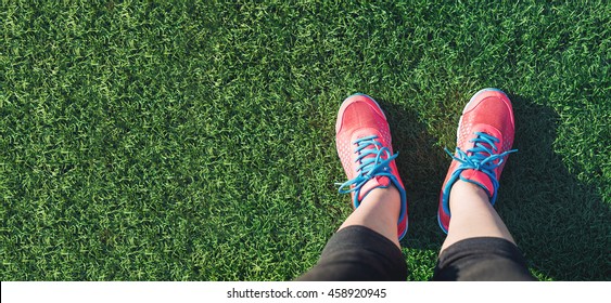 Female Runner Looking Down At Her Feet In A Grass Field