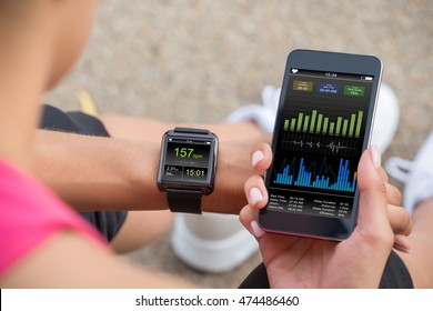 Female Runner Looking At Her Mobile And Smart Watch Heart Rate Monitor - Powered by Shutterstock