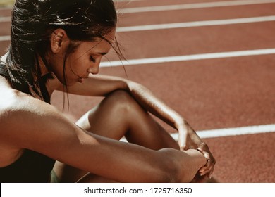 Female runner looking tired after workout session. Sportswoman feeling exhausted after a training session at running track. - Powered by Shutterstock