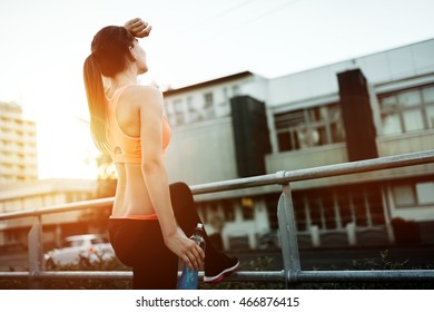 Female Runner Resting And Drinking Water