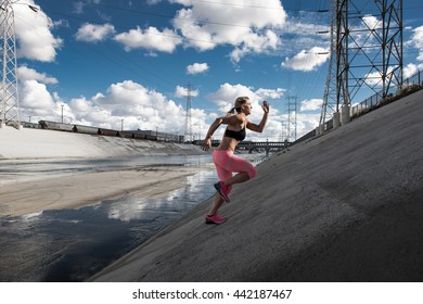 Female Runner Running Up Steep River Aqueduct, Los Angeles, California, USA