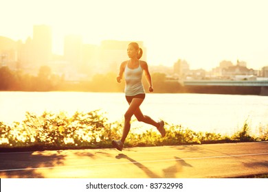 female runner running at sunset in city park. Healthy fitness woman jogging outdoors. Montreal skyline in background. - Powered by Shutterstock