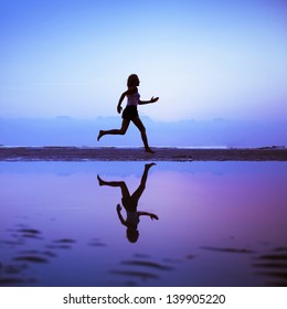 Female Runner Silhouette Is Mirrored Below With A Blue Sunset Sky As Background