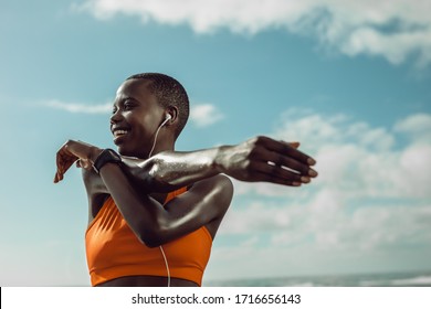 Female runner stretching hands at the beach. Woman exercising outdoors in the morning. - Powered by Shutterstock