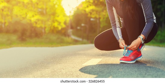 Female runner tying her shoes preparing for a run a jog outside  - Powered by Shutterstock