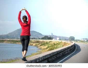 Female Runner Warm Up To Prepare To Exercise.