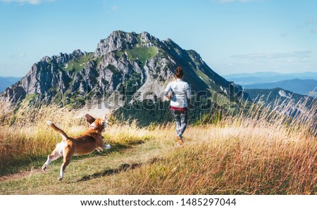 Female running by the mounting range path with her beagle dog back view. Canicross running healthy lifestyle concept image. 