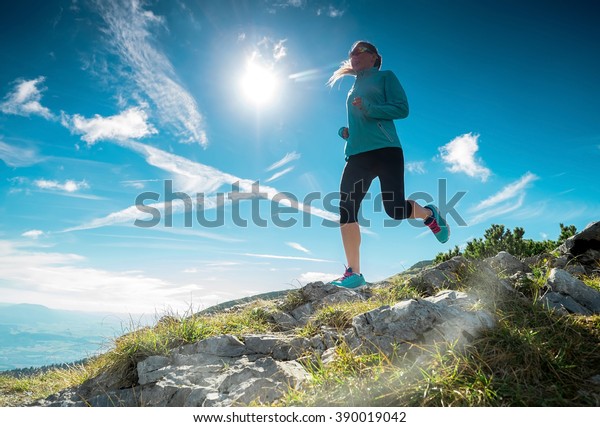 Female running in\
mountains under\
sunlight.