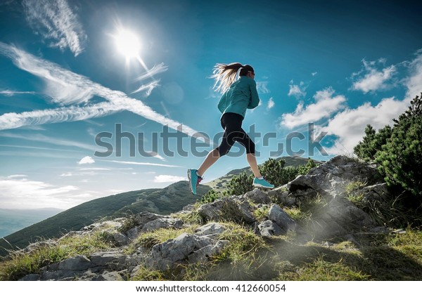Female running in\
mountains under\
sunlight.