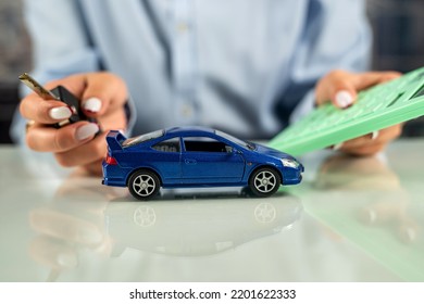 Female Sales Representative Used Two Hand-held Small Model Cars. An Employee Of A Car Rental Company. Ideas For Renting And Buying A Car With Insurance