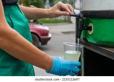 A Female Salesman Pours Mohito From A Barrel Into A Disposable Glass. Street Trade