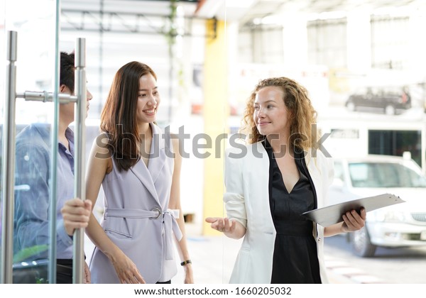 The\
female salesperson is offering a Price list for the customer to buy\
a new car. signing a document and talking trading car, car service\
check, car reantal Automobile In Dealership\
Store