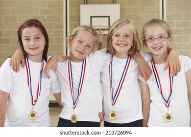 Female School Sports Team In Gym With Medals