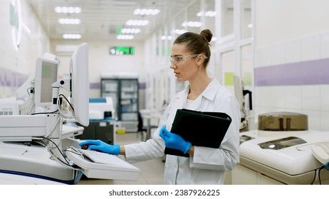 A female scientist controls the operation of devices for laboratory research. Modern laboratory technologies. Medical research centrifuge. - Powered by Shutterstock