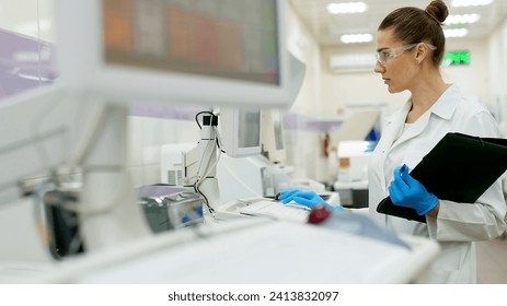 A female scientist controls the operation of devices for laboratory research. Modern laboratory technologies. Medical research centrifuge. - Powered by Shutterstock