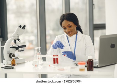 Female Scientist In Gloves Work With Microscope And Laptop