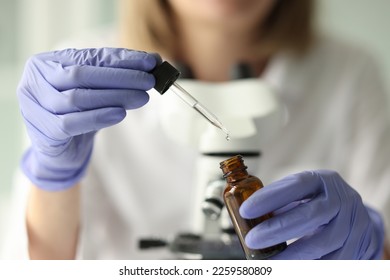 Female scientist holding pipette and vial close up. Woman in latex gloves taking liquid by pipette for her scientific experiments. - Shutterstock ID 2259580809