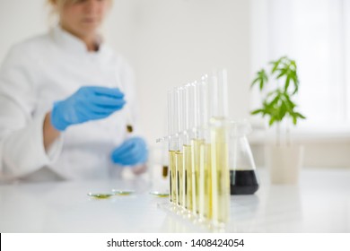 Female scientist in laboratory testing cbd oil extracted from a marijuana plant. She is using a various glass tubes and bowls for the experiment. Healthcare pharmacy from medical cannabis.