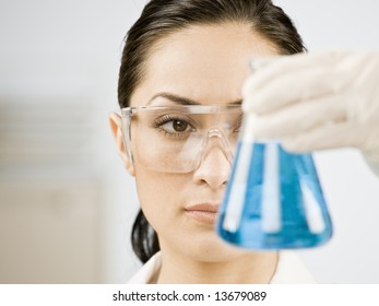 Female Scientist Looking At Beaker Of Liquid