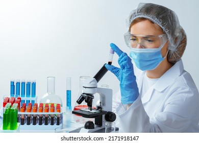 Female Scientist Looking At Test Tube With Blood Sample In Laboratory