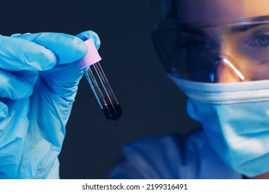 Female Scientist Looking At Test Tube With Blood Sample In Laboratory