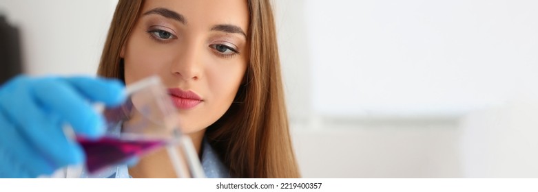 Female Scientist Pour Pink Liquid From Flask In Medical Chemistry Lab