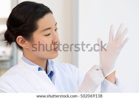Female scientist putting on gloves
