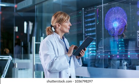 Female Scientist Uses Tablet Computer In The Modern Brain Study Laboratory And Monitors EEG Reading And Brain Model Functioning.