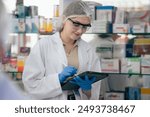 Female scientist using digital tablet for recording data of lab experiment standing at the drug storage