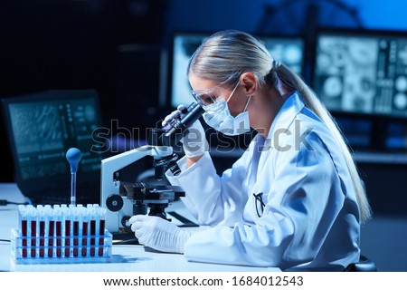 Female scientist working in modern lab. Doctor making microbiology research. Laboratory tools: microscope, test tubes, equipment. Coronavirus covid-19, bacteriology, virology, dna and health care.